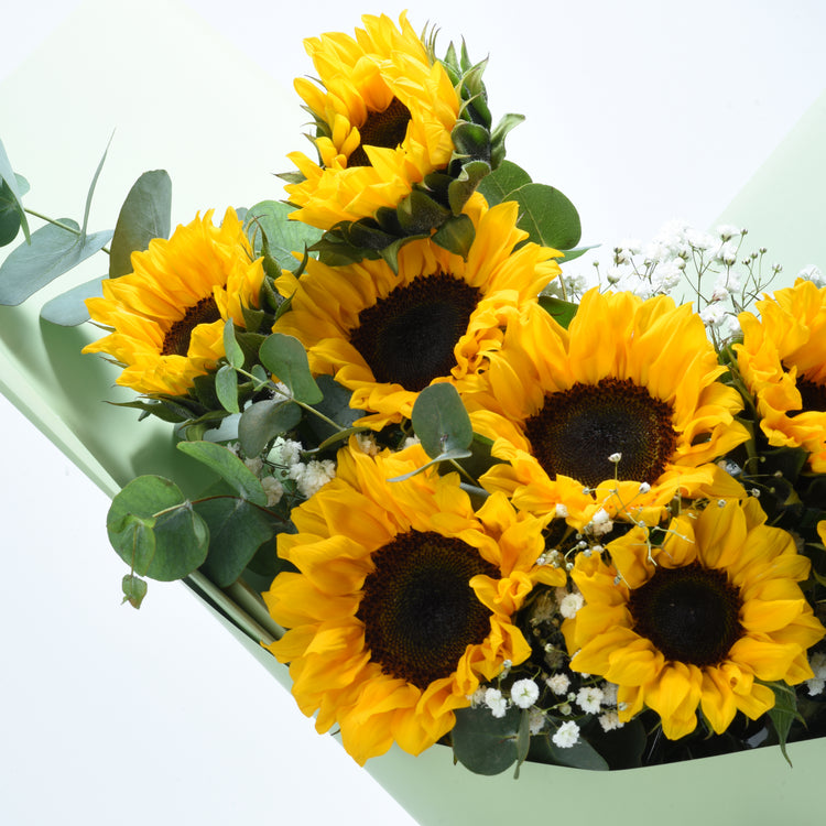 Vibrant yellow sunflowers with dark centers, accented by green eucalyptus and white baby’s breath.