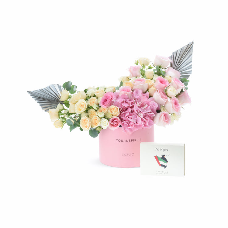 Pink box holds blush roses and hydrangeas, accented with metallic wings and matching card.