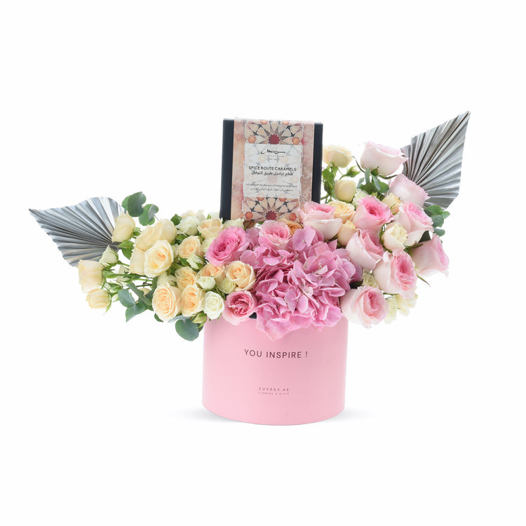 Pink box holds blush roses, hydrangeas, and caramel gift, accented with metallic fans.