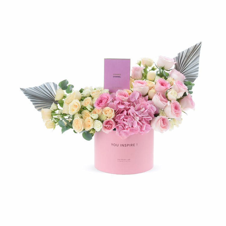 Pink floral arrangement with angel wings and Chanel perfume in branded box.