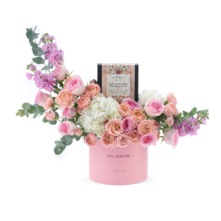 Pink floral arrangement with roses, hydrangeas, eucalyptus, and spice caramel chocolates in a "YOU INSPIRE!" box.