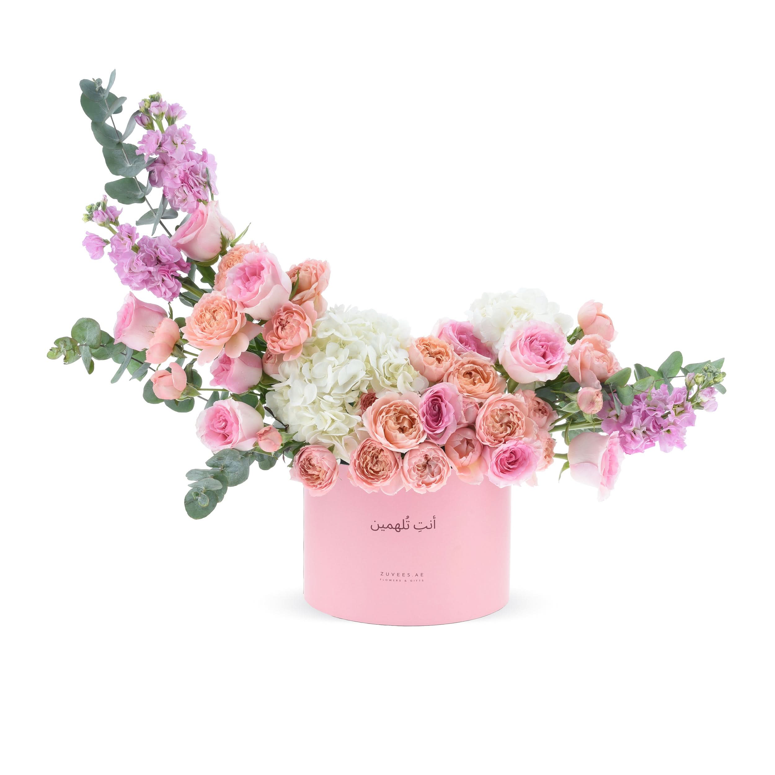 Soft pink roses, hydrangeas, and eucalyptus in elegant pastel pink cylindrical box.