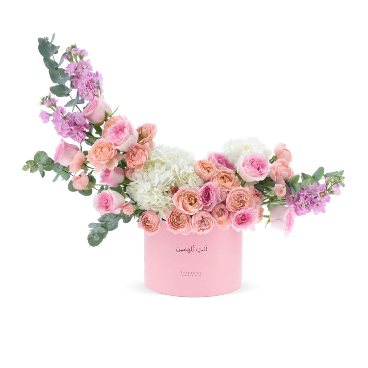 Soft pink roses, hydrangeas, and eucalyptus in elegant pastel pink cylindrical box.