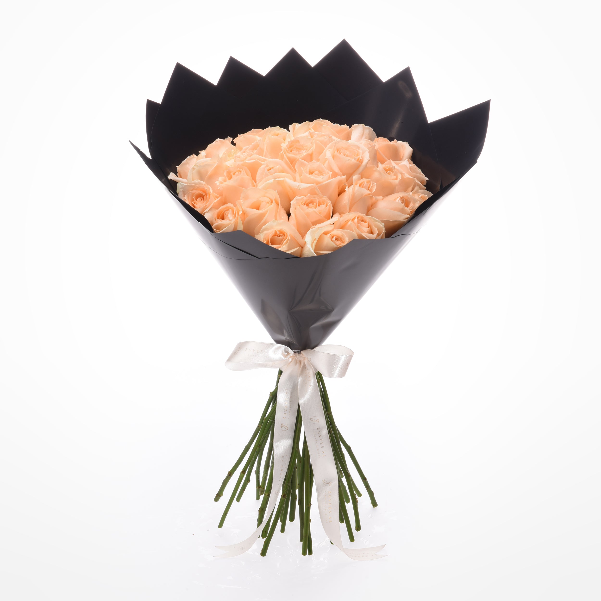 Soft peach roses in sleek black paper, tied with elegant white ribbon.