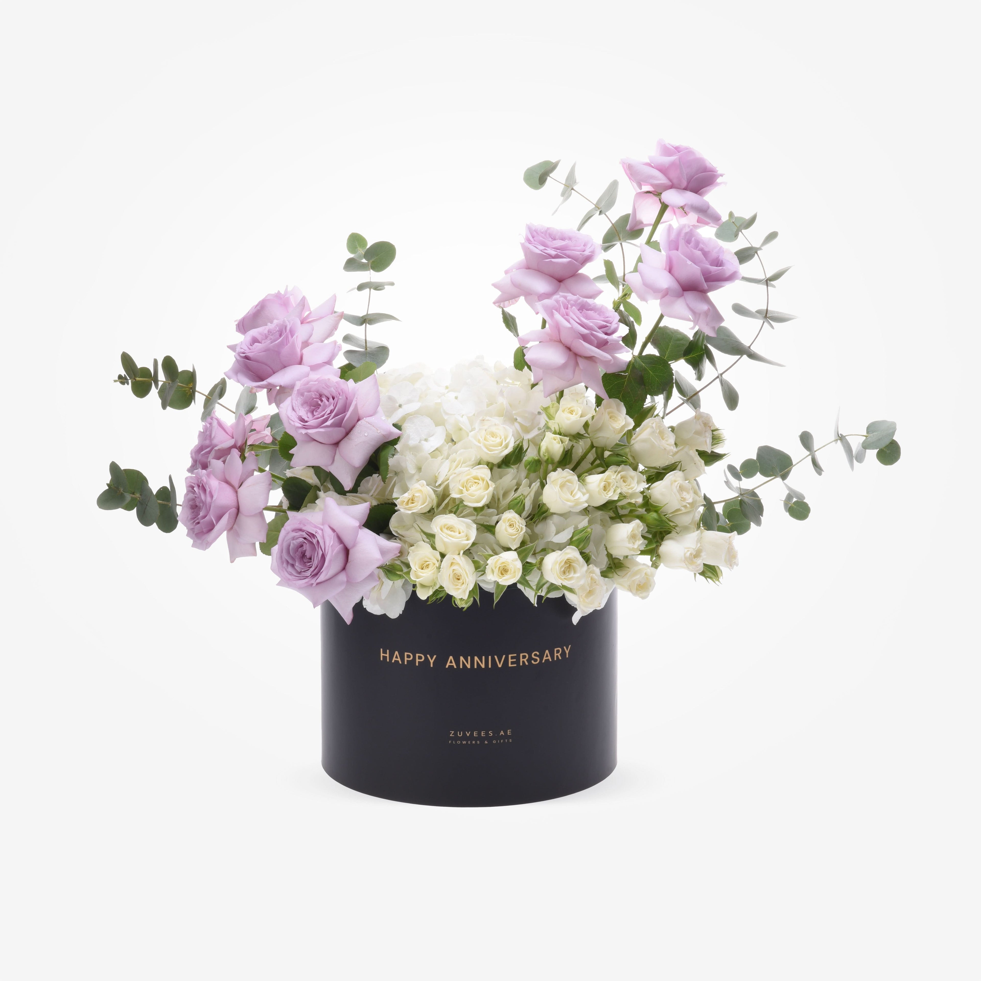Elegant lavender roses and white blooms in sleek black anniversary box.