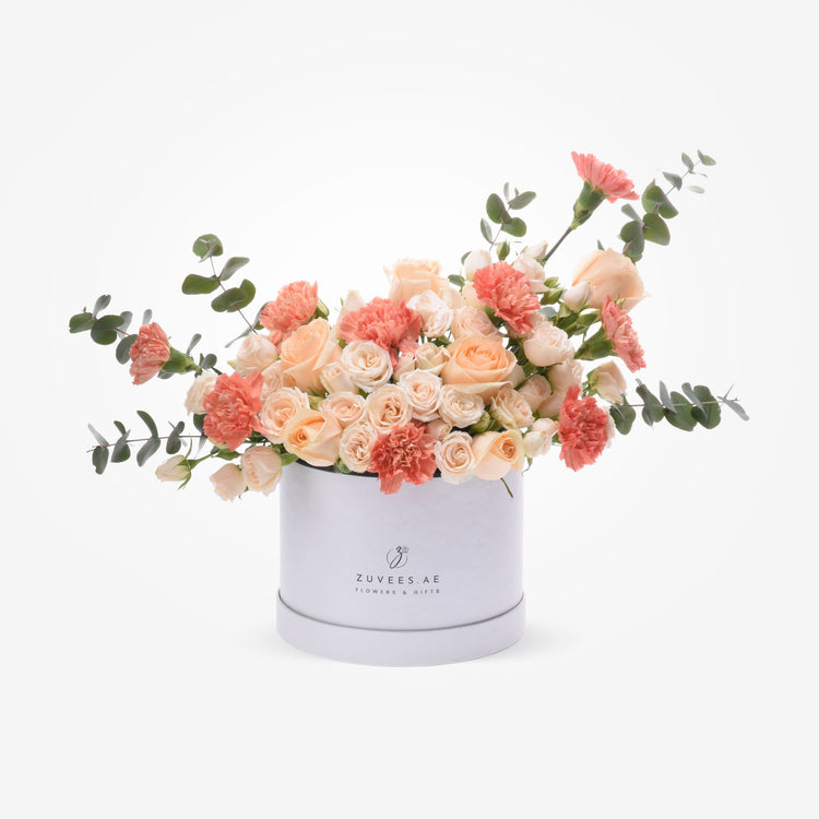 Soft peach roses and carnations in elegant white hat box.