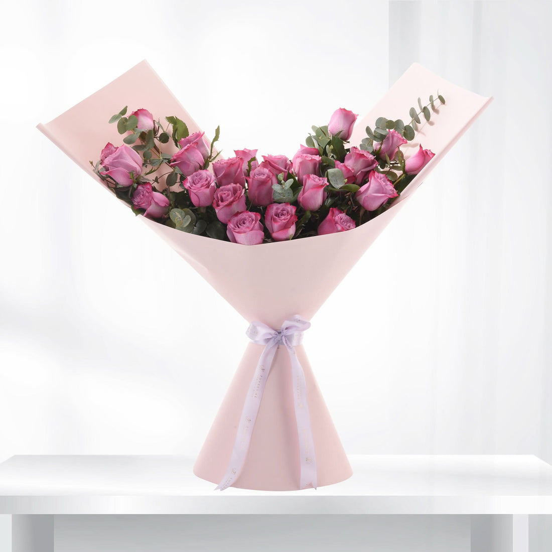 Soft pink roses elegantly wrapped in matching paper with lavender ribbon.