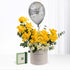 Vibrant yellow roses with white accents, silver "Happy Birthday" balloon, and branded gift box.