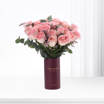Pink roses in burgundy vase with "Happy Birthday" text, elegant gift arrangement.