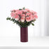 Soft pink roses in deep burgundy vase with eucalyptus and lavender accents.