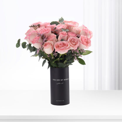 Pink roses in black vase with bilingual message, minimalist white background.