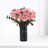 Pink roses in black vase with bilingual message, minimalist white background.