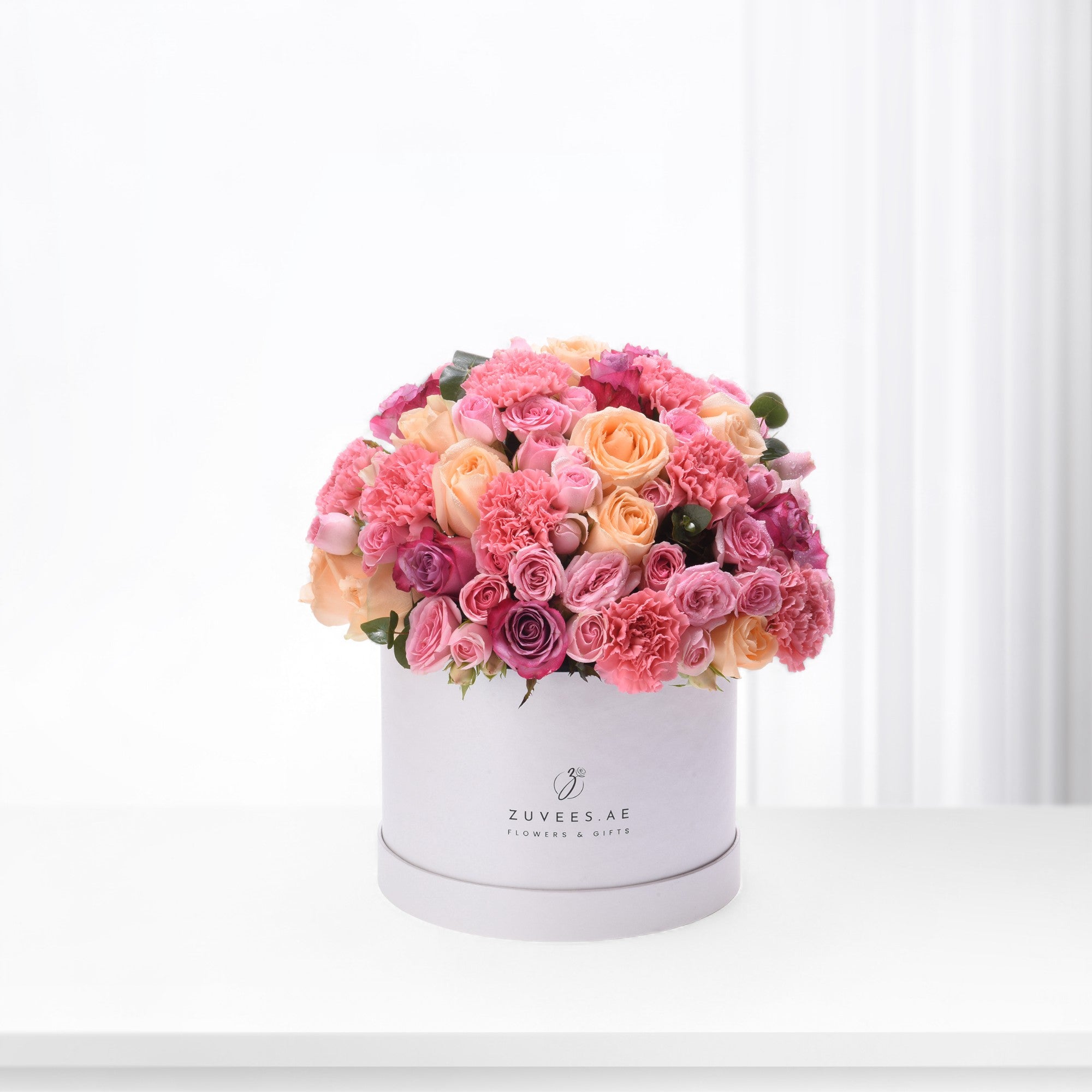 Pink and peach roses, carnations in white hat box.