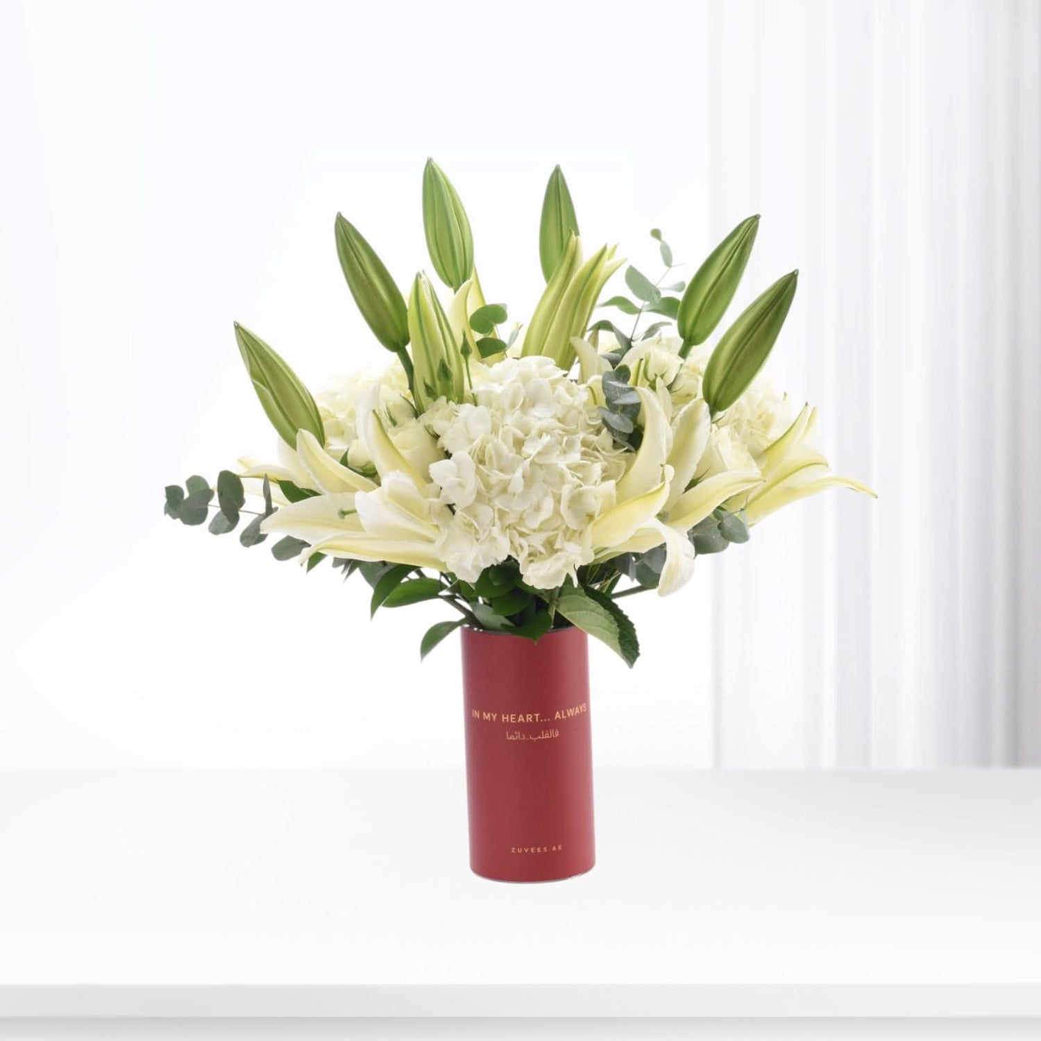Elegant white lilies and hydrangeas in a bold red vase with heartfelt message.