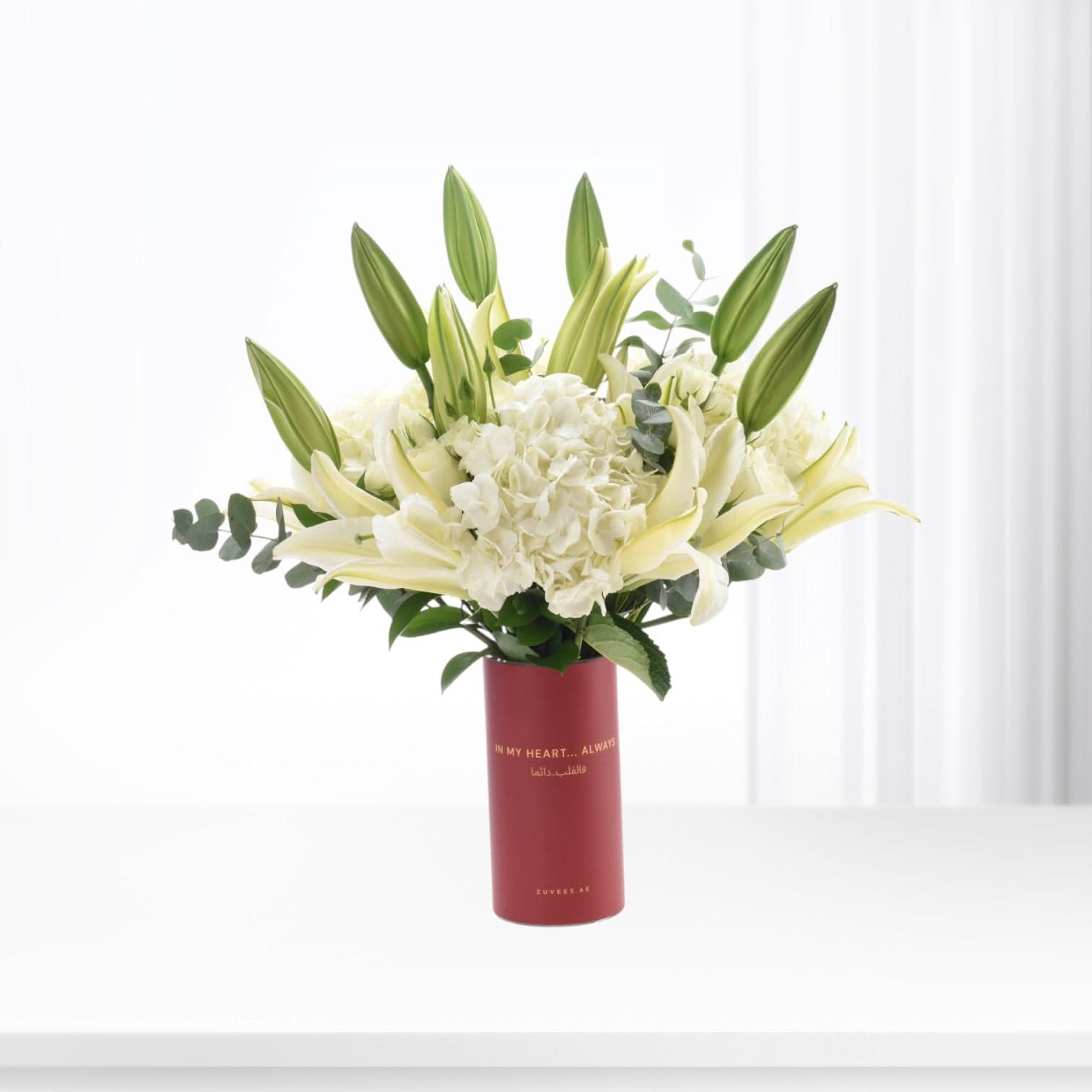 Elegant white lilies and hydrangeas in a bold red vase with heartfelt message.