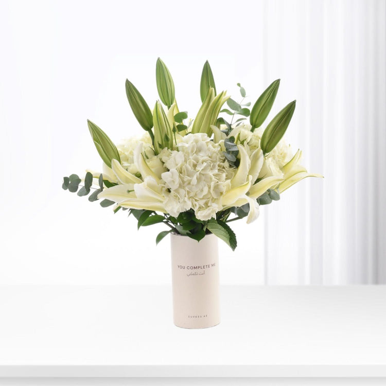 White lilies and hydrangeas in minimalist vase with bilingual message.