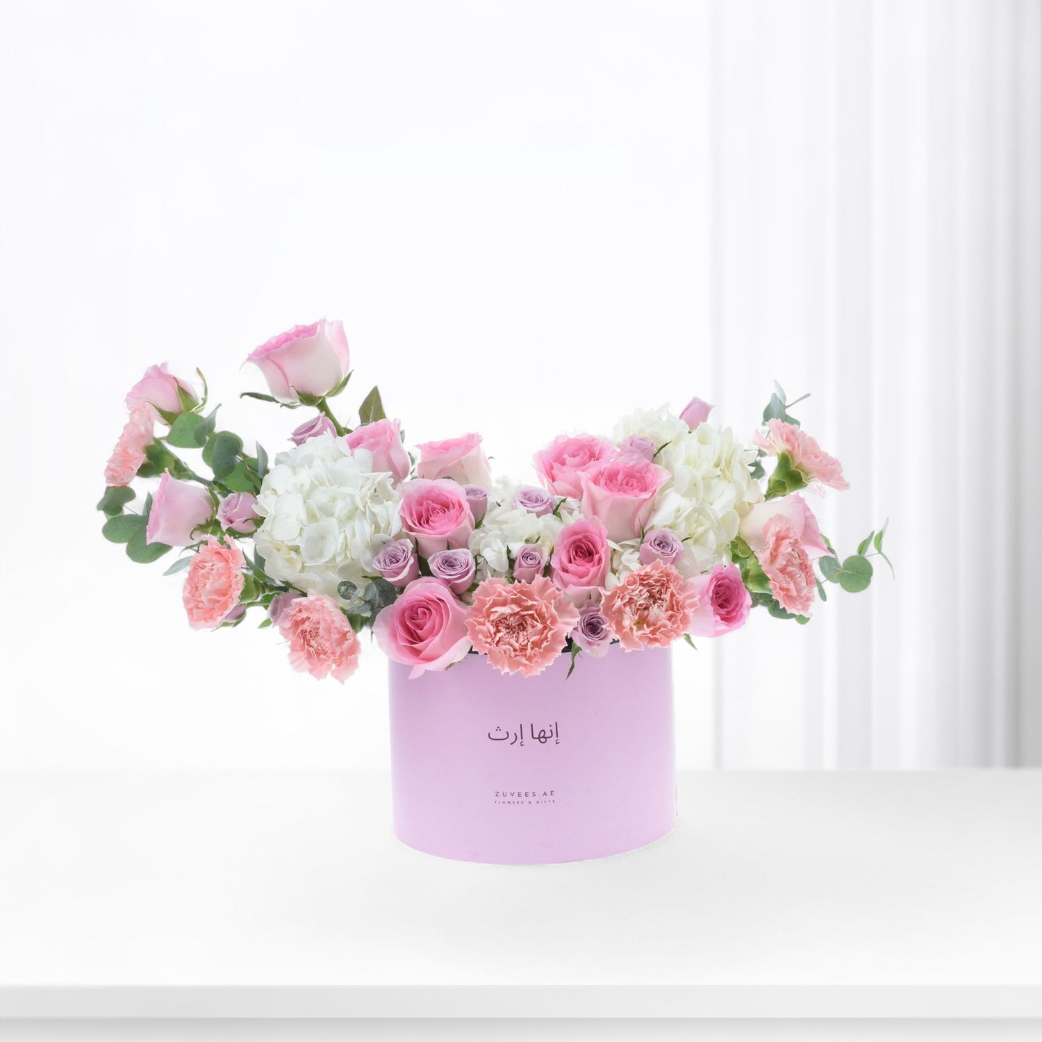 Pastel pink roses, carnations, and hydrangeas in a lavender box.