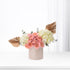 Elegant pastel floral arrangement with gold accents in minimalist container.