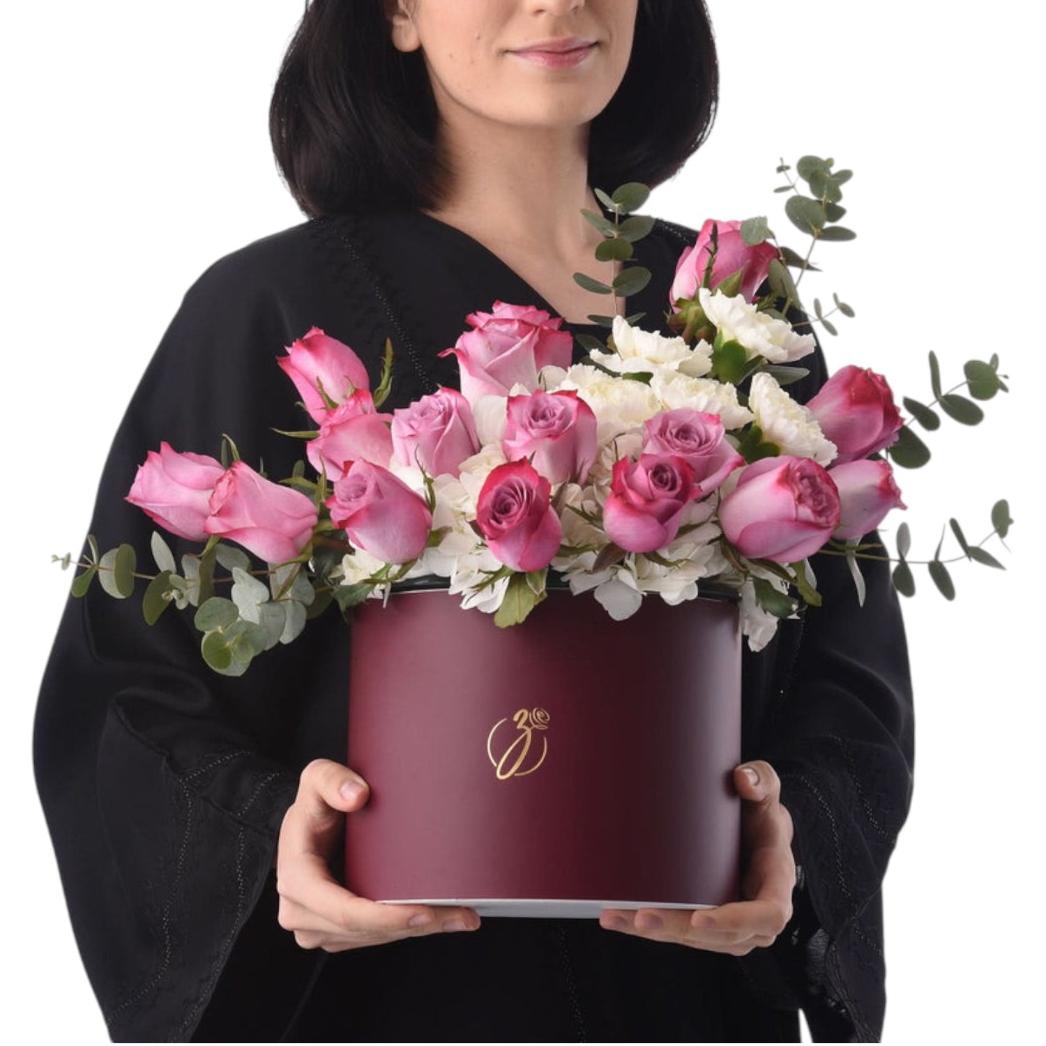 Woman holds burgundy hat box filled with pink roses and white blooms.
