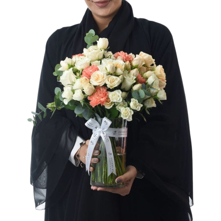 Elegant white and coral roses in clear vase with branded white bow.