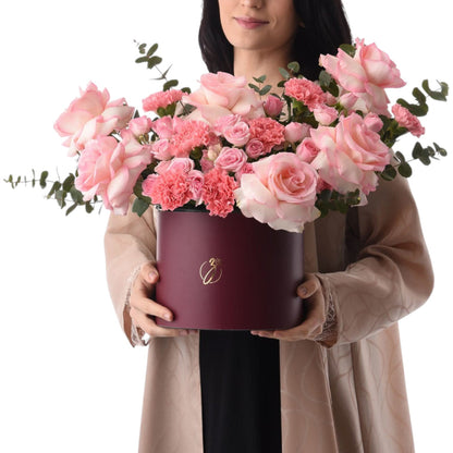 Elegant burgundy hat box filled with lush pink roses and carnations.