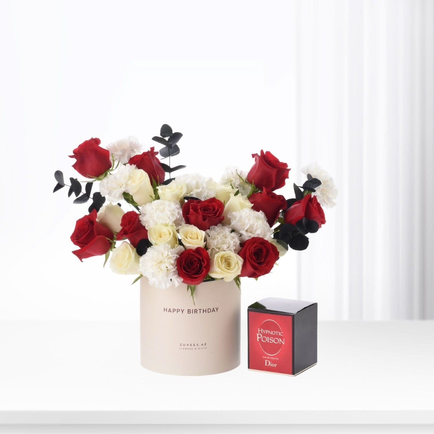 Red and white roses with black eucalyptus in "Happy Birthday" box, beside Dior Hypnotic Poison perfume.