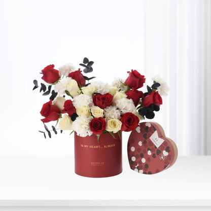 Red and white roses with black eucalyptus in a heart-shaped box.