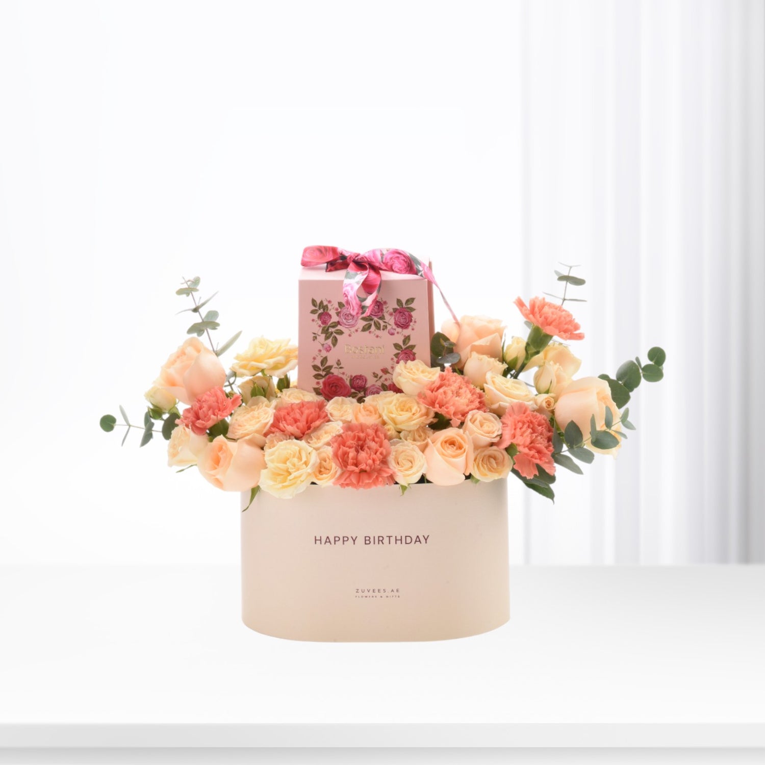Pastel pink and peach roses with carnations, eucalyptus, and a "Happy Birthday" box.