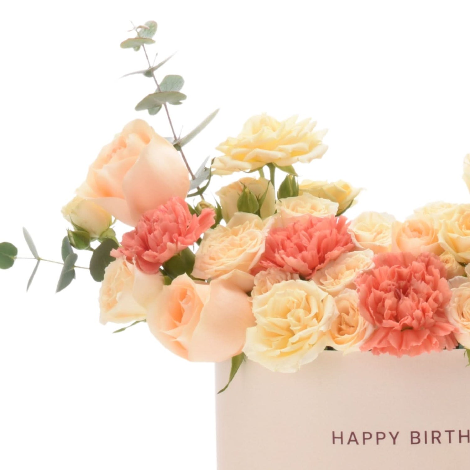 Pastel peach roses and coral carnations in white box with "Happy Birthday" text.