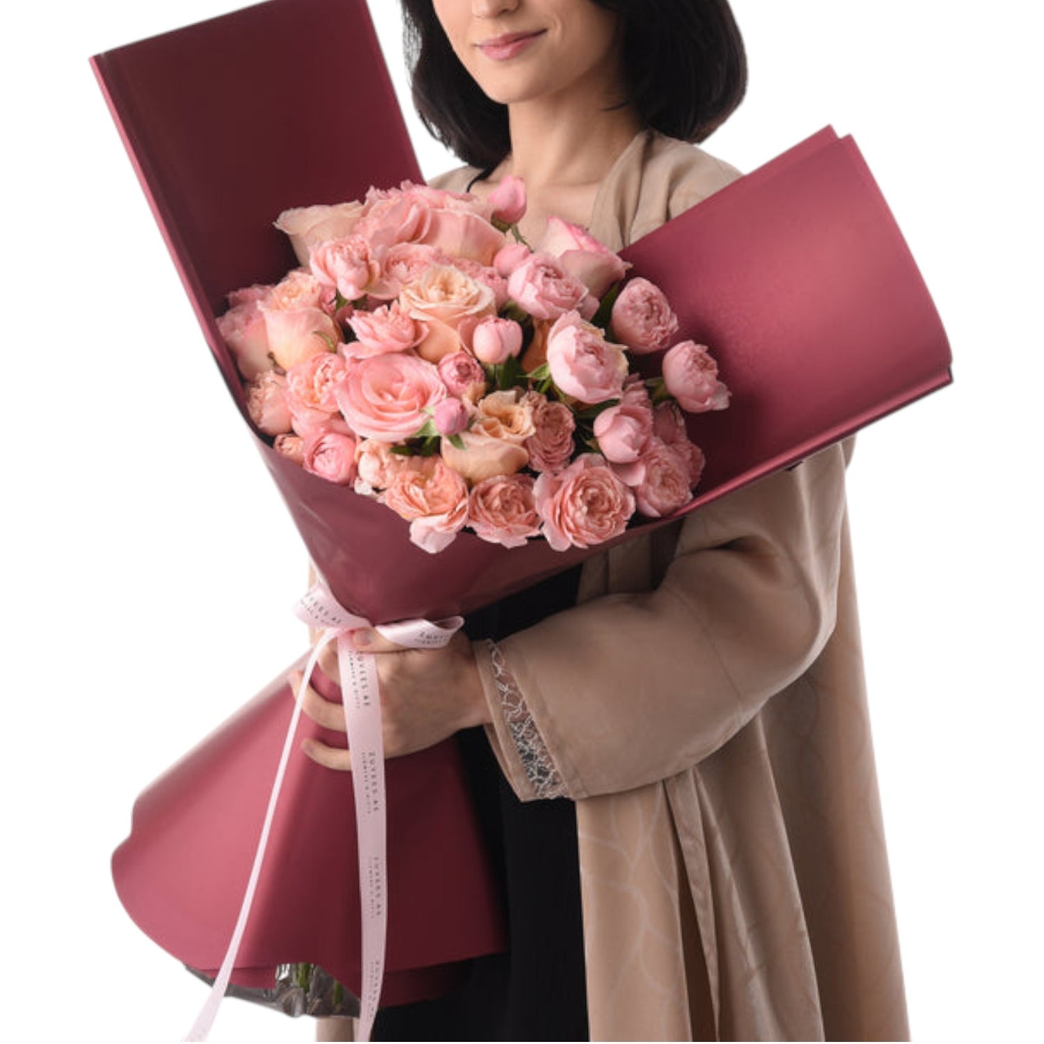 Soft pink roses in rich burgundy wrap, held gently by a smiling woman.