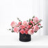 Elegant pink roses and carnations in sleek black box with gold logo.