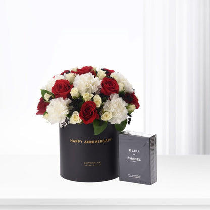 Elegant black anniversary hat box with red roses and white carnations, paired with Bleu de Chanel perfume.