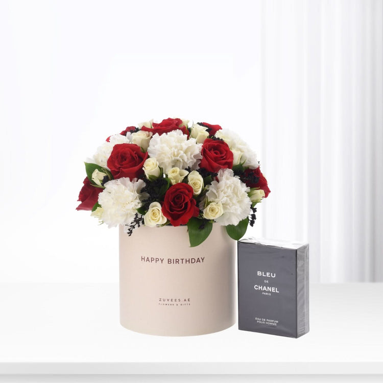 Elegant red and white roses in beige box beside Chanel Bleu perfume.