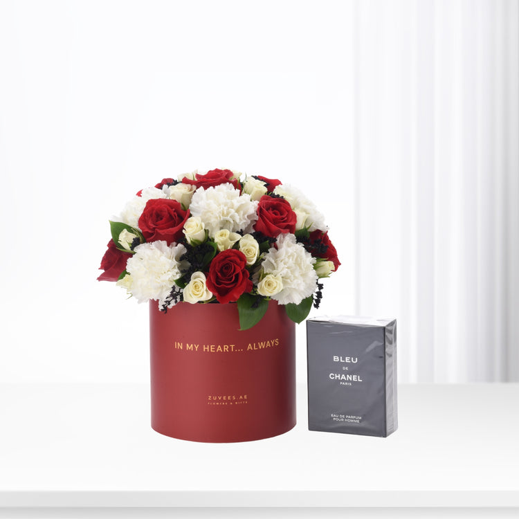 Red cylindrical box with red and white roses, beside Chanel Bleu de Chanel perfume.