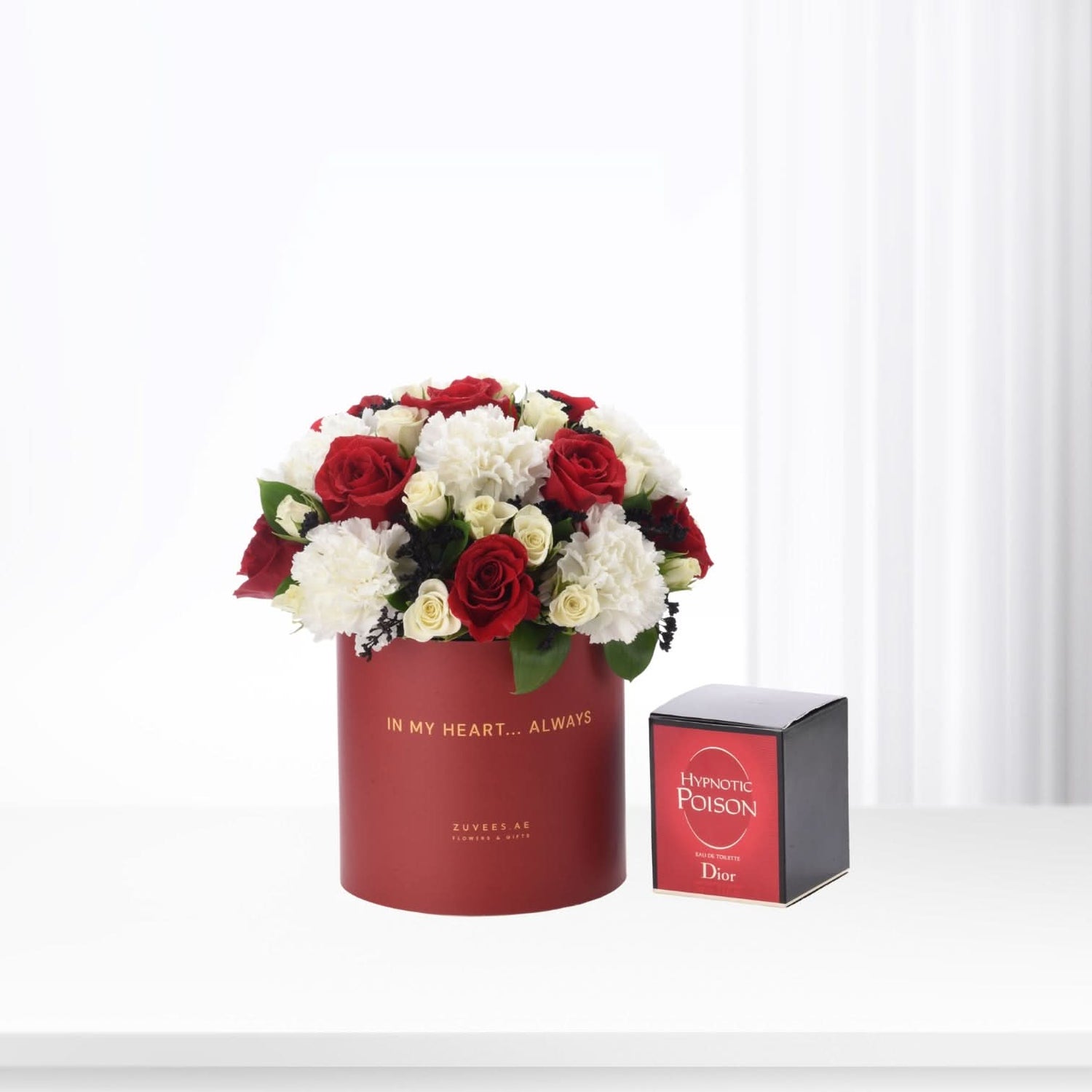 Red and white roses in a red box with "In My Heart... Always" text, beside Dior Hypnotic Poison perfume.