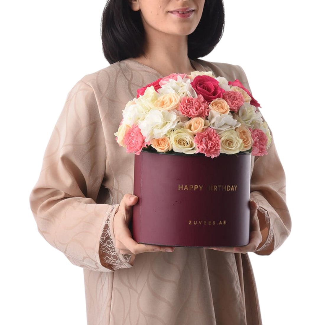 Woman holds burgundy "Happy Birthday" box filled with vibrant pink, peach, and white roses.