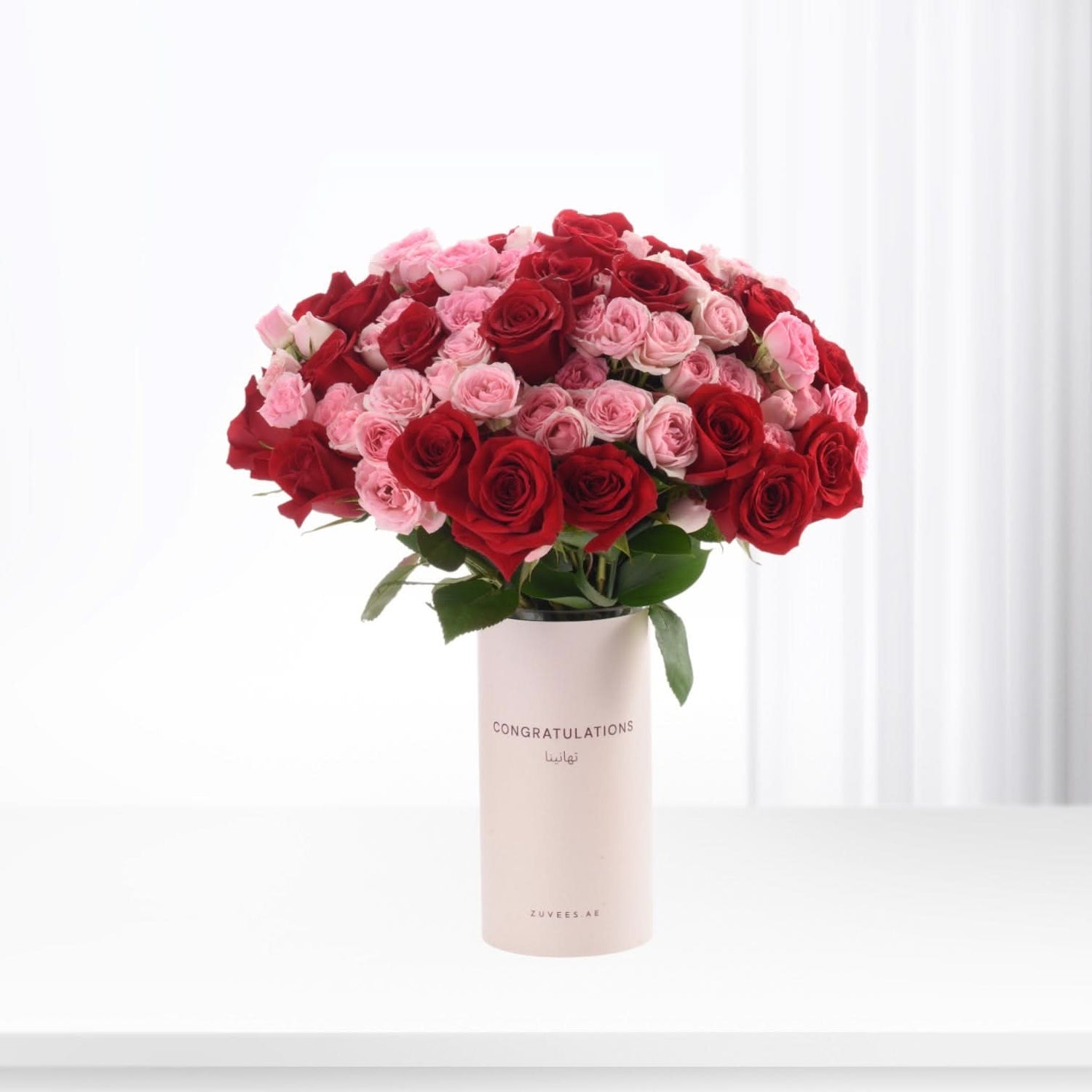 Vibrant red and pink roses in minimalist vase with "Congratulations" text.
