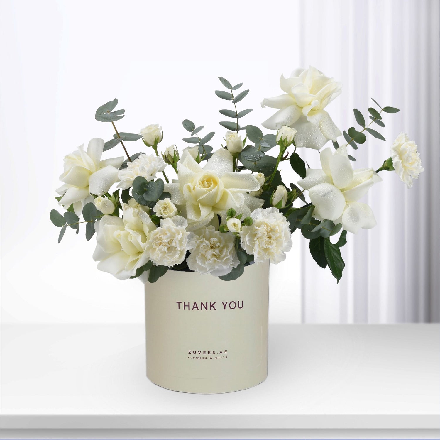 Elegant white rose and carnation bouquet in "Thank You" branded cream cylinder.