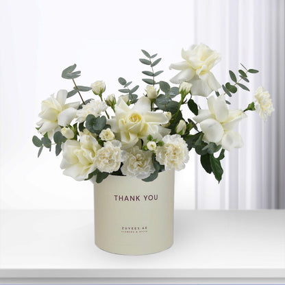 Elegant white rose and carnation bouquet in "Thank You" branded cream cylinder.