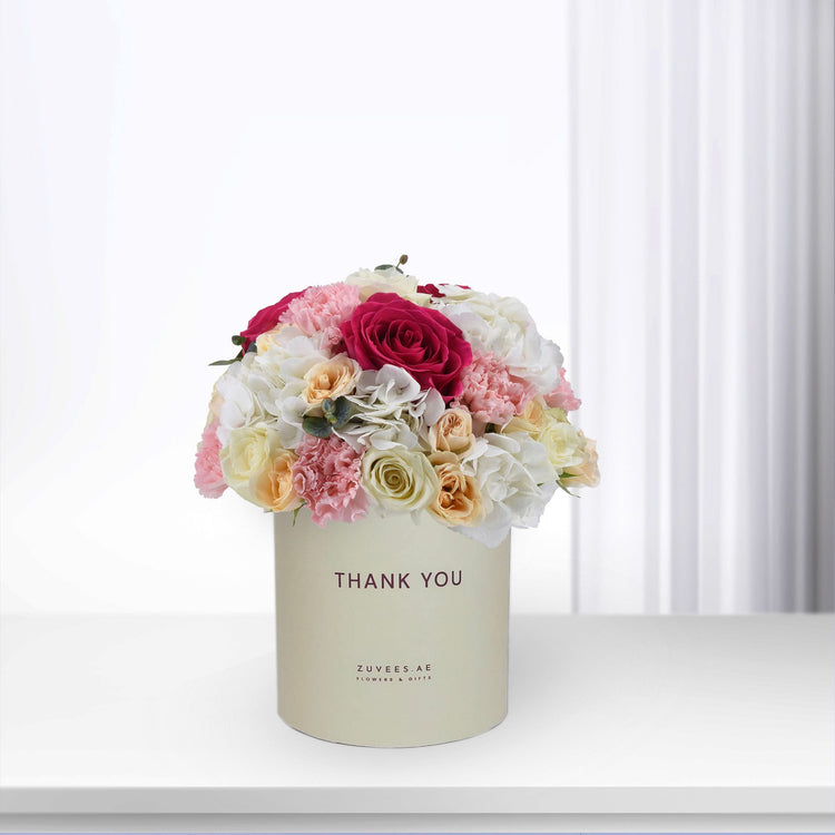 Cream box holds vibrant pink, white, and peach roses and carnations, "Thank You" printed.