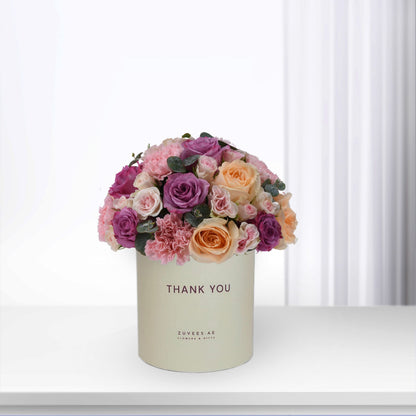 Pastel pink, purple, and peach roses in cream box reading "Thank You".