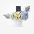 Elegant blue hydrangeas and cream roses in white box with silver wings and Chanel perfume.