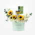 Pastel green box holds sunflowers, white roses, and M&S tea/marmalade.
