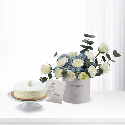 White cake and floral arrangement in minimalist birthday gift set.