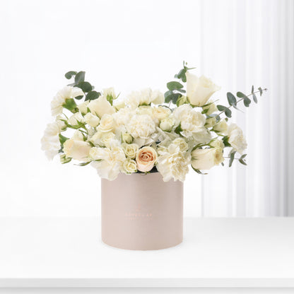 Elegant ivory roses and carnations in blush box, minimalist white backdrop.