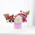 Pink box holds vibrant red, pink, and white roses with gold leaf accents.