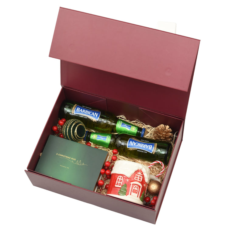 Rich burgundy gift box holds Barbican malt, festive mug, and holiday decorations.
