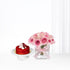 Vibrant red velvet cake beside blush pink roses in glass vase, elegant gift set.