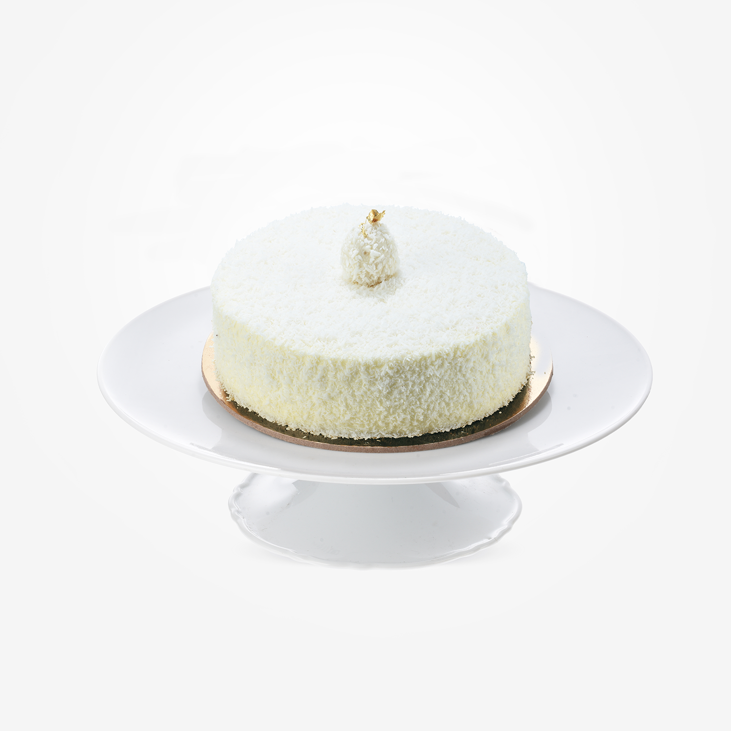White coconut cake topped with gold leaf, elegantly displayed on a white cake stand.