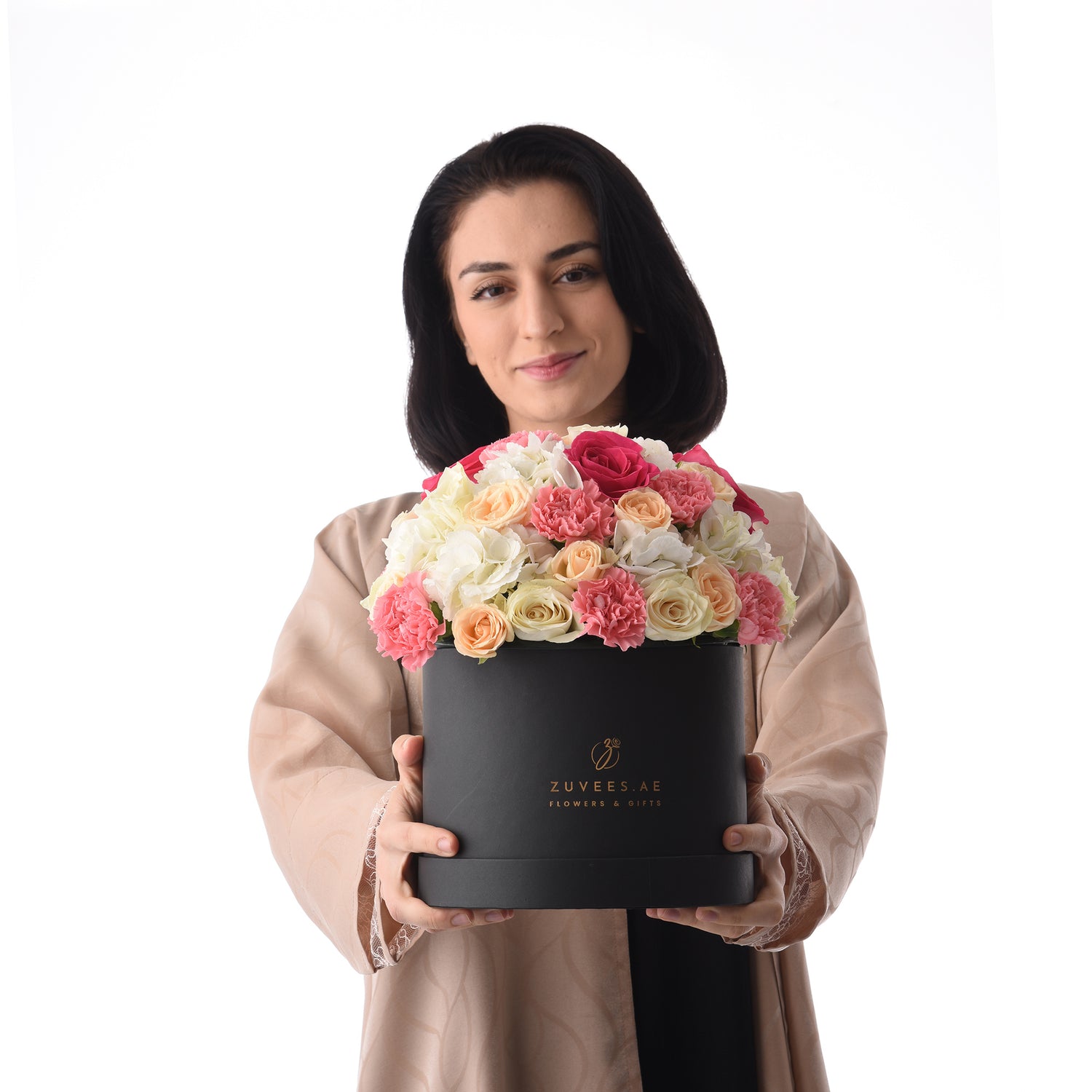 Elegant woman holds luxurious black box overflowing with vibrant pink, peach, and white roses.